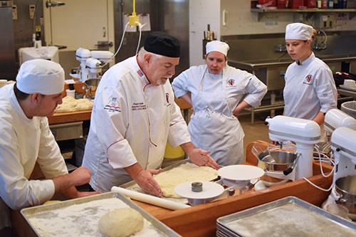 Chef Frank showing students pastry rolling techniques.