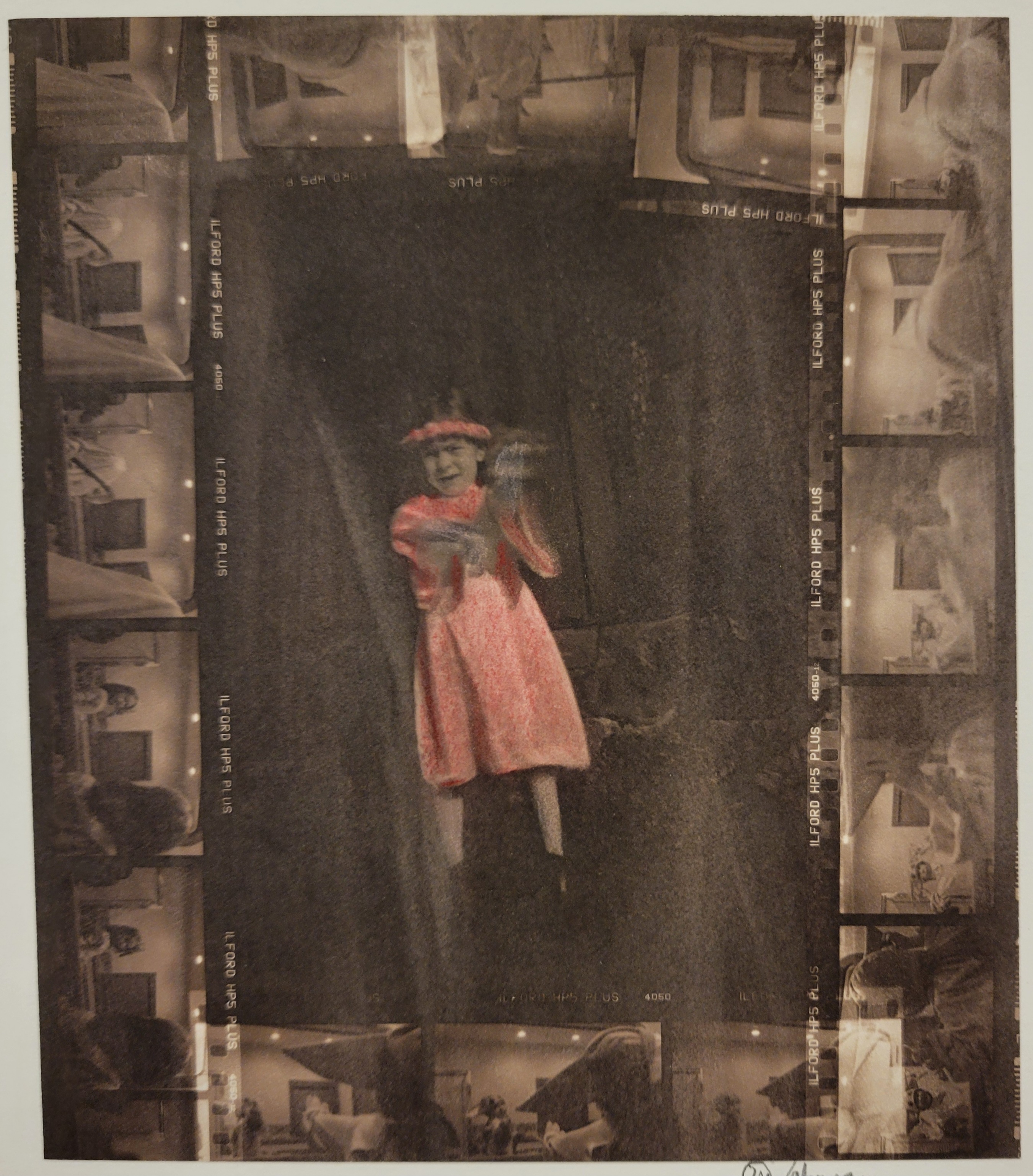 A hand colored contact print. It depicts a young girl in a hand tinted red dress