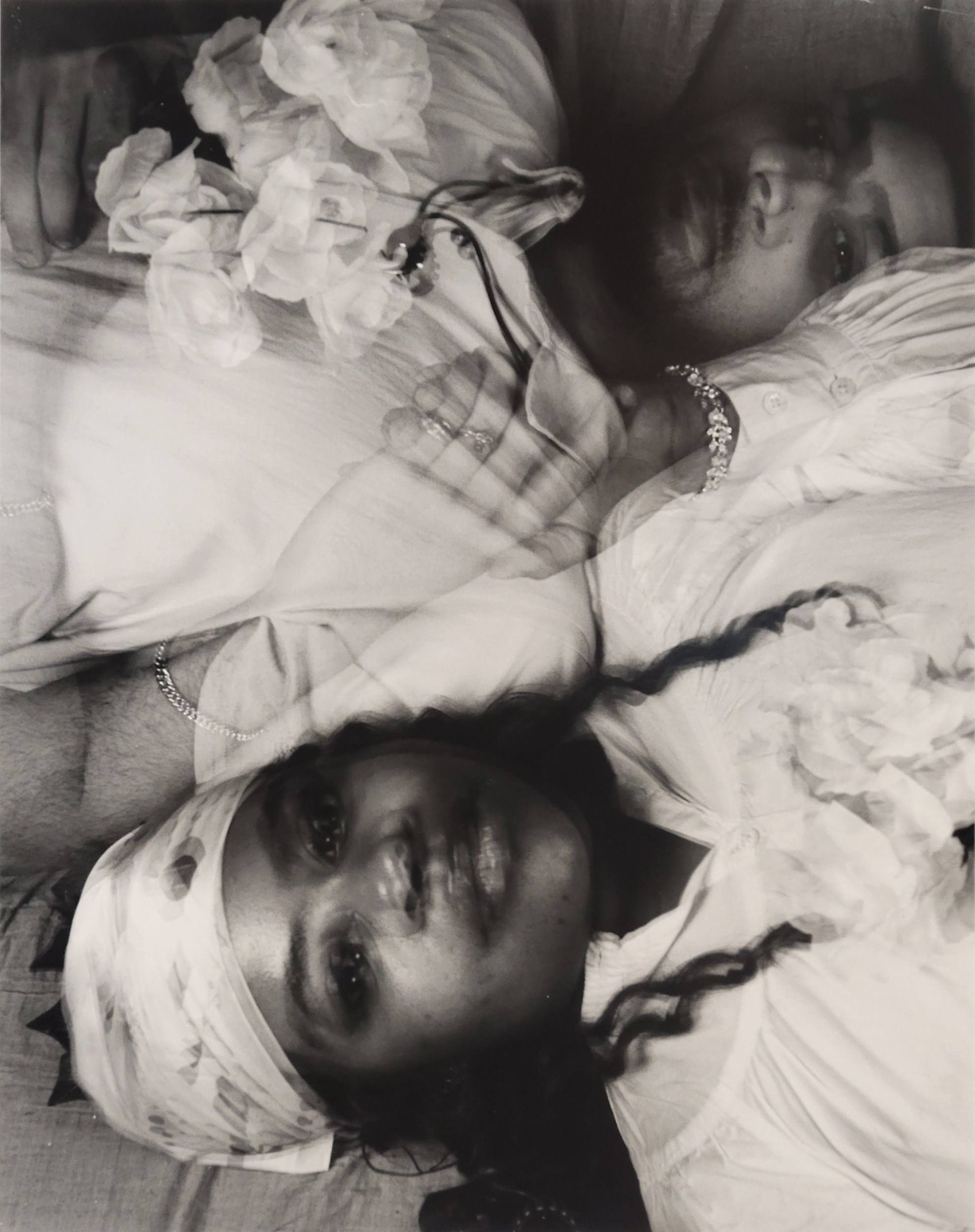A portrait black and white photo. Two blurred face are looking at the camera. They are laying down with their heads pointing in opposite directions