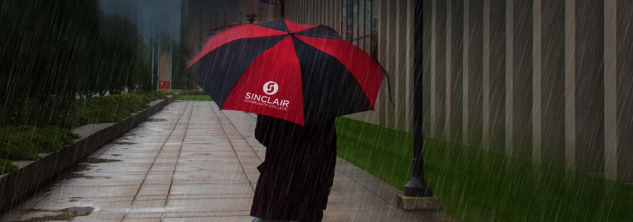 Person walks with Sinclair Umbrella in Heavy Storm Rain on Campus as