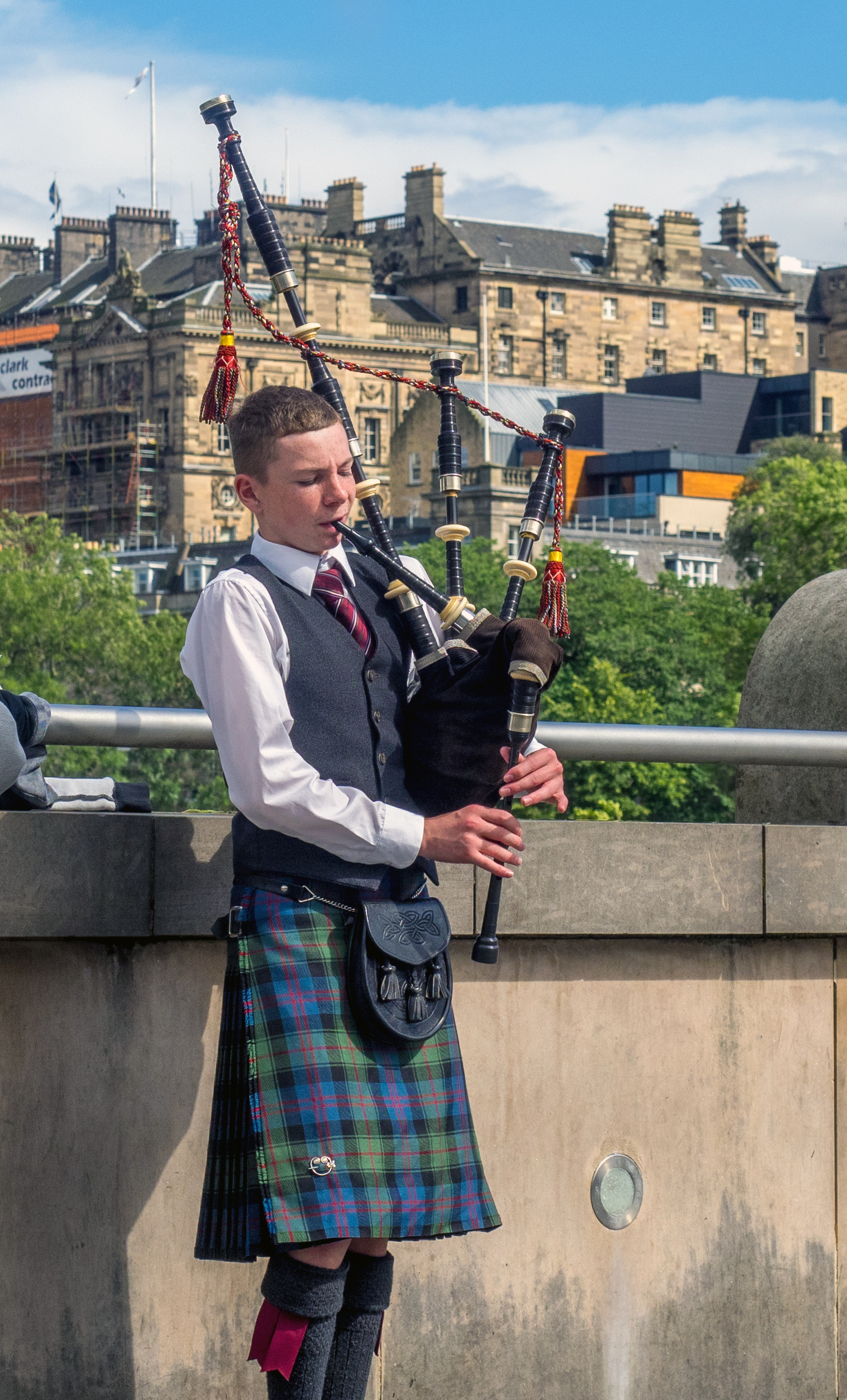 Edinburgh, UK - July 26, 2017: Unidentified Bagpiper playing music with bagpipes along the Mound on July 26, 2017 in Edinburgh Scotland. There are many bagpipers busking and entertaining tourists!