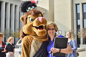 The Sinclair Lion mascot walking across a Downtown Dayton street with Sinclair employees.