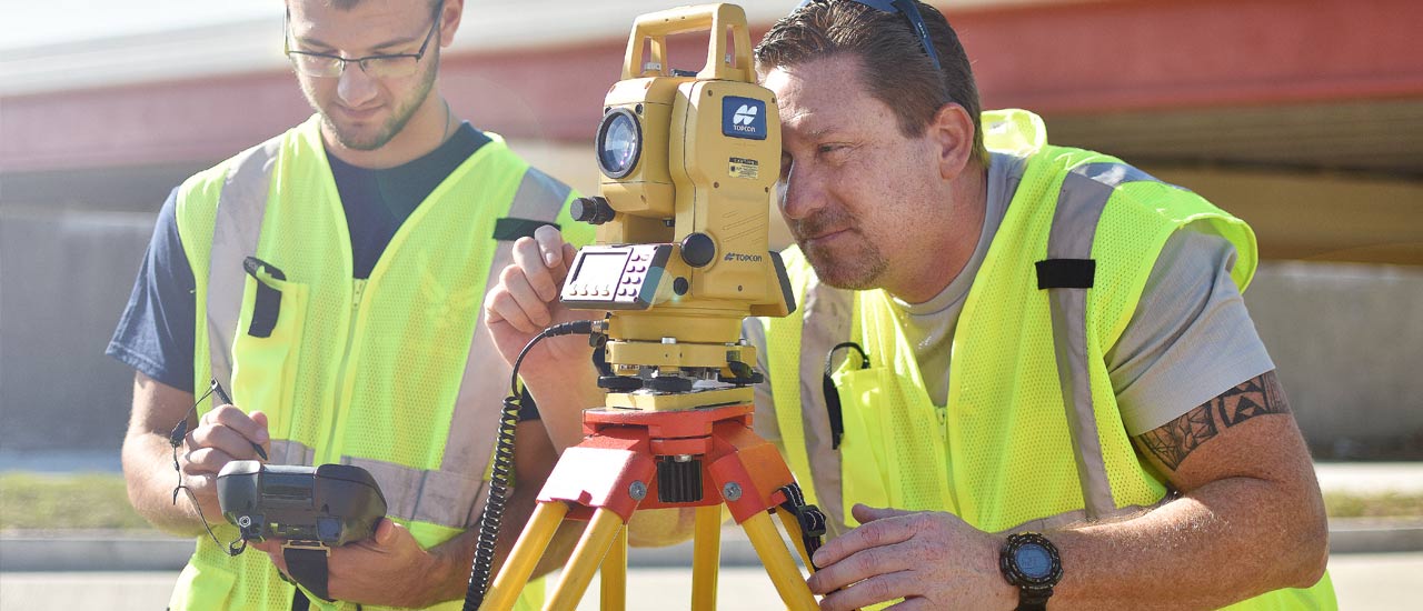 Two students using survey equipment to survey the Sinclair Dayton campus.